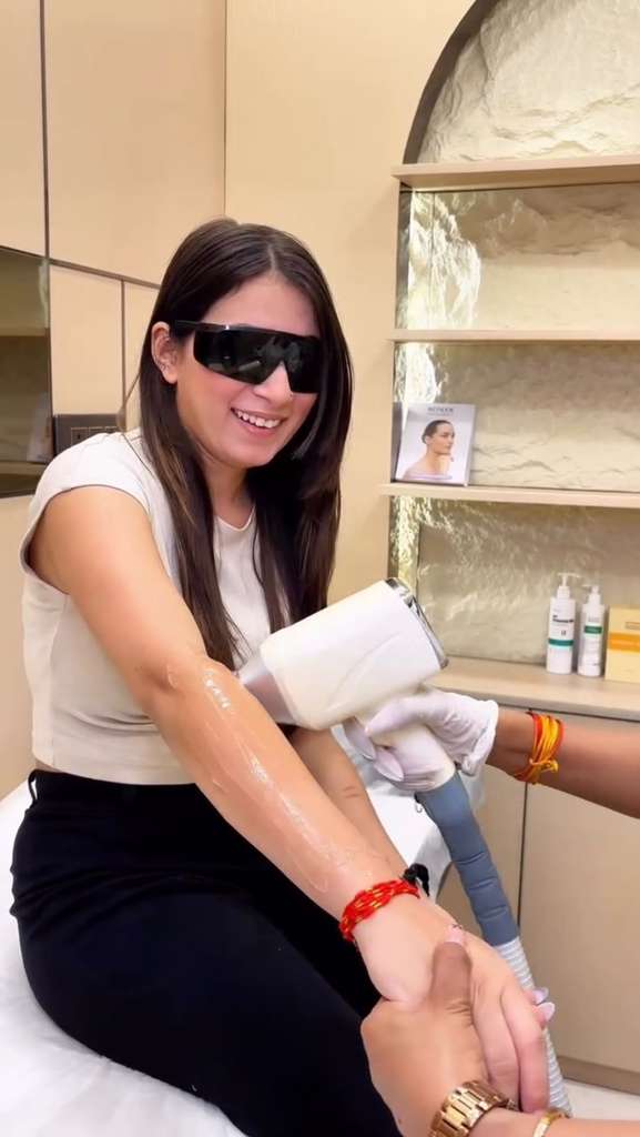 Woman receiving laser hair reduction treatment on her arm using advanced laser technology.