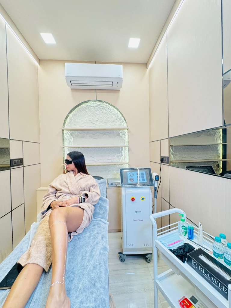 Modern laser hair reduction treatment room with advanced laser equipment and client prepared for treatment.
